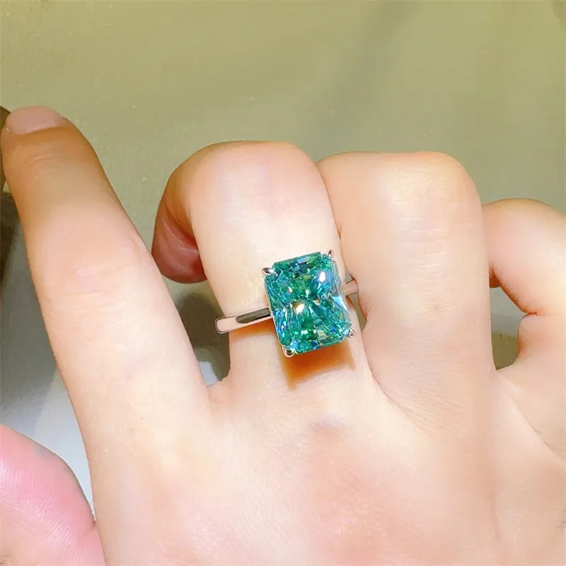 Green gemstone ring on a person's finger with a neutral background