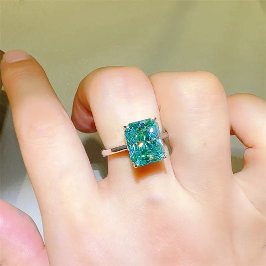 Green gemstone ring on a person's finger with a neutral background