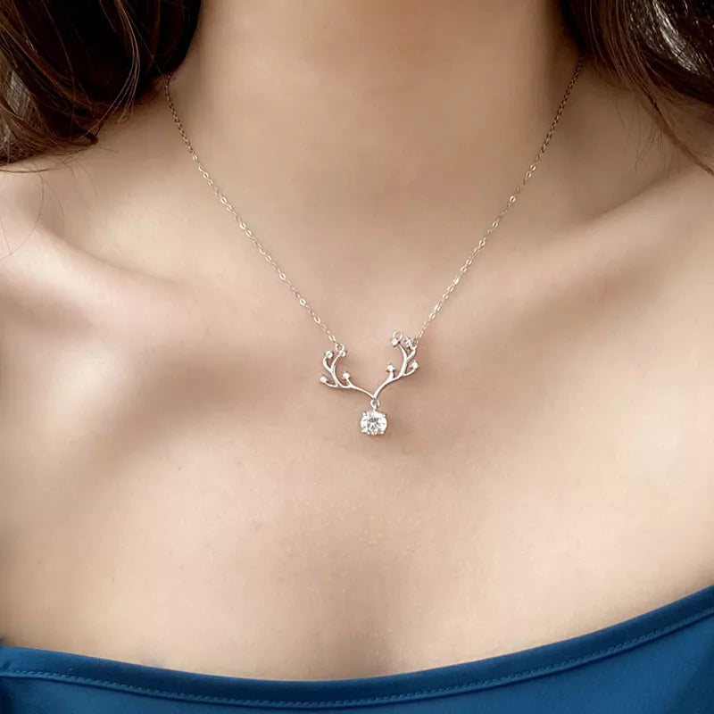 Necklace with a delicate pendant on a person wearing a blue top