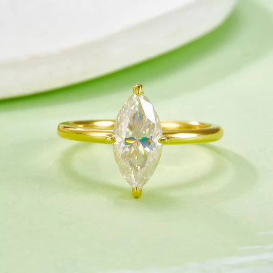 Gold ring with a marquise-shaped gemstone on a light green background