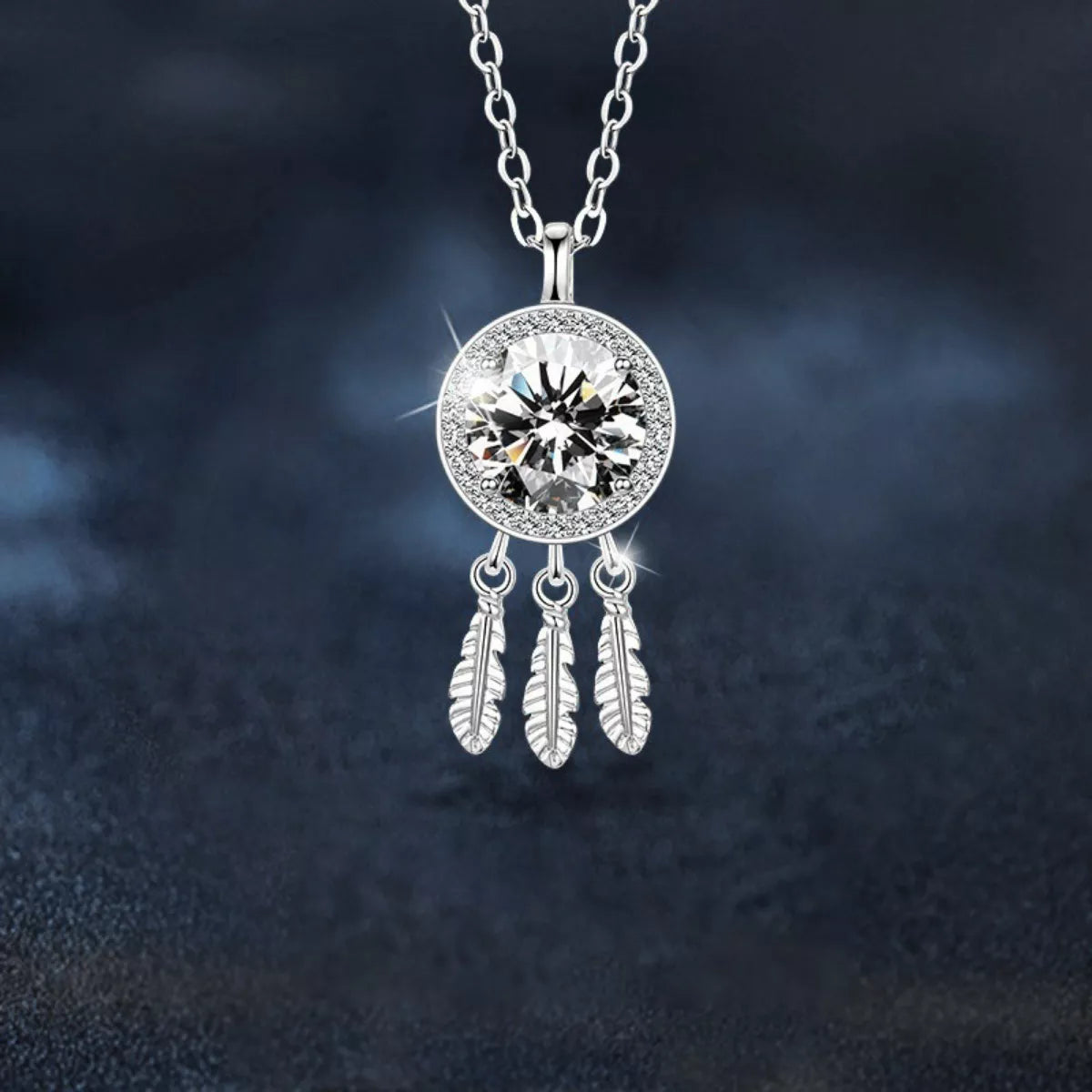 Silver necklace with a round pendant and feather charms on a dark background